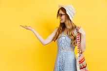 Young Woman, In A Summer Hat, Pointing And Looking To The Left At A Logo, Showing An Advertisement, On A Yellow Background.