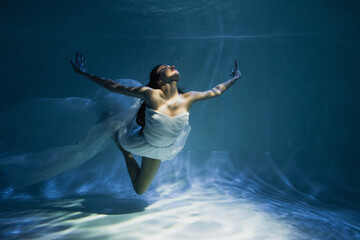 Wall Mural - lighting on young woman in white dress diving in swimming pool