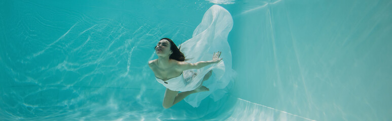 Wall Mural - pretty young woman in dress swimming in pool with blue water, banner