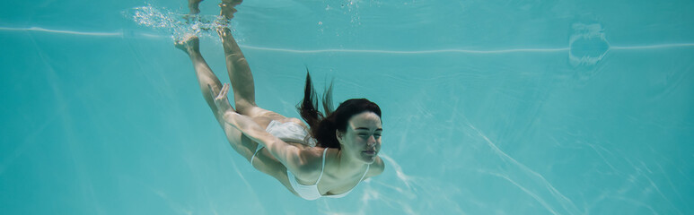 Wall Mural - young woman in white swimsuit diving in pool, banner