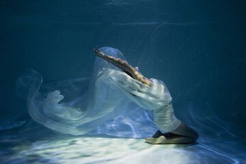 Wall Mural - lighting on young woman in white elegant dress sitting in pool