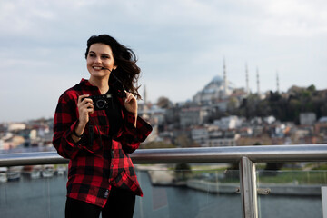 Young woman tourist standing with photo camera on the bridge. Beautiful woman traveling around the city.