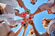 © artiemedvedev - Low angle view of friends having fun at poolside summer party, clinking glasses with colorful summer cocktails near hotel swimming pool. People toast drinking fresh juice at luxury villa on vacation.