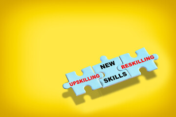 New skills upskilling reskilling on blue puzzle on yellow background. Skills development concept and business success idea