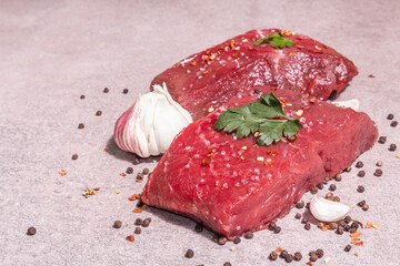 Raw beef steaks on a grey stone background