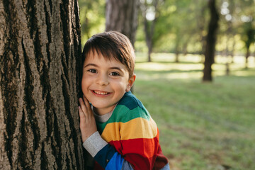 portrait of young cute boy leaned on tree in public park