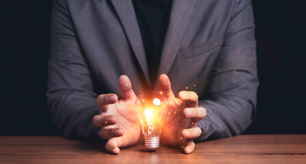 Poster - businessman hand protecting with lightbulb with virtual brain glowing , patent and creative idea inn