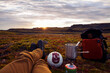 Wanderer legt eine Pause, Rast bei Sonnenuntergang auf einer großen Wiese ein und brüht sich einen Kaffee mit Hilfe einer Gaskartusche bzw Gasbrenners begleitet vom Volleyball wie bei Cast Away 