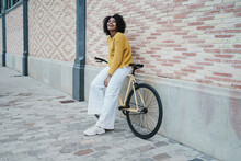 Portrait Of A Delighted African American Woman Standing On Cool Yellow Urban Bike