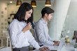 © amnaj - Side view Asian businesswoman drinking coffee  using tablet businessman sitting beside modern office.