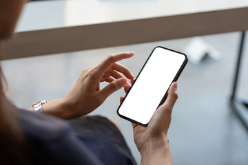 Close up businesswoman hand holding a smartphone blank white screen at the office. mock up.