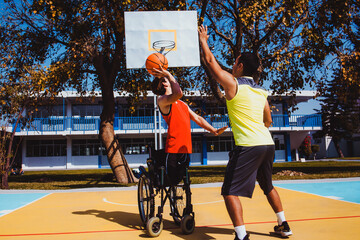 mexican young man using wheelchair and playing basketball with a friend in Mexico disability person