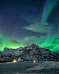 Wall Mural - aurora borealis with starry over snowy mountain and nordic village at night in flakstad, lofoten isl