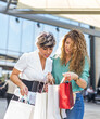 © antoniosantosc - Two shopping friends looking at the contents of their bags in a mall