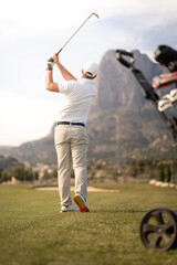 Golf player making a perfect swing on the golf course in the sunset.