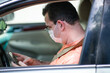 Young Man Using Cellphone Putting on Seatbelt in car  Wearing a Medical Mask