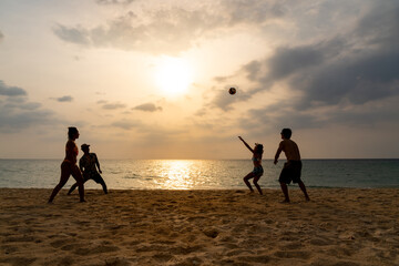 Wall Mural - Group of Asian man and woman friends playing beach volleyball together on tropical beach in sunny day. Male and female friendship enjoy and having fun outdoor lifestyle activity on summer vacation