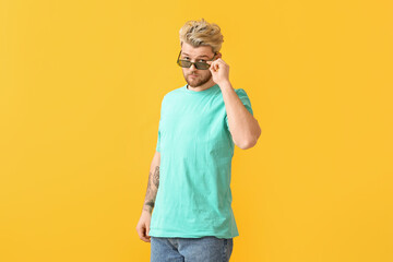 Poster - Young man with stylish sunglasses on color background