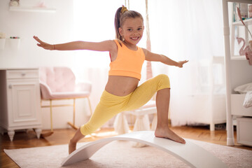 Wall Mural - Little girl doing a workout in the bedroom at home.