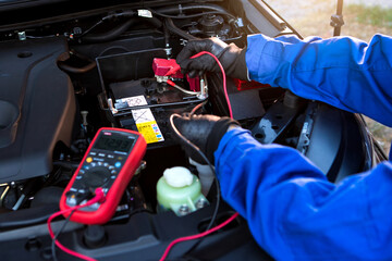 Technician uses multimeter voltmeter to check voltage level in car battery. Service and Maintenance car battery.