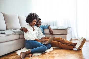 young black couple sit on the floor using laptop, side view. people, leisure, mutliethnic relationsh