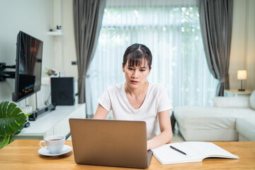 Asian woman working on computer at home during COVID-19 pandemic.