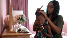 African American Mother Combing  Her Little Daughter Hair Sitting Near Mirror On Dressing Table In The Children Room At Home. Black Mom And Girl At Bedroom In Morning Time Together