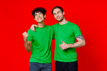 Two man green t-shirts embrace emotions friendship red background