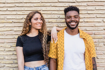 Portrait of a happy multiracial couple in love smiling together in a brick background