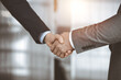 © rogerphoto - Business people standing and shaking hands in sunny office, close-up. Handshake and marketing