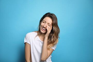 Sticker - Cheerful young woman laughing on light blue background