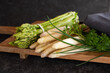 Fresh green and white asparagus with herbs on wooden cutting board. Healthy vegetables. Background for seasonal gastronomy.