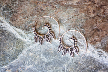 Wall Mural - Silver metal decorative oriental spirale design earrings on natural neutral background