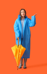 Poster - Stylish young woman in raincoat and with umbrella on color background