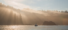 Atmospheric Golden Light Sunbeams Through Morning Mist And Fog Over An Ocean Fishing Boat Off The Pacific Coast Of Vancouver Island Near Port Renfrew, BC, Canada.