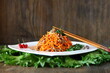 Carrot Korean meat salad with chopsticks on wooden oak table