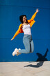 © Mikel Taboada/Westend61 - Happy young woman with arms outstretched jumping high on footpath