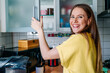 © Oxana Guryanova/Westend61 - Happy woman with gray eyes opening door of cabinet in kitchen at home