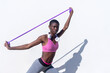 © Rafael Fernandez Torres/Westend61 - Young female athlete stretching arms with rubber band against white wall during sunny day