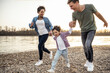 © Uwe Umst√§tter/Westend61 - Boy holding hands of parents while running over pebble by lake