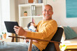 © steve brookland/Westend61 - Smiling father looking away while holding sleeping daughter and digital tablet in living room