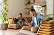 © steve brookland/Westend61 - Man using smart phone while girlfriend playing with Pug dog in background at home