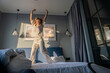 © Vasily Pindyurin/Westend61 - Happy woman dancing while standing on bed in the morning