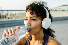Adult Sportswoman With Headphones Drinking Water From Bottle