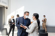 © LIGHTFIELD STUDIOS - middle aged businessman in medical mask talking to asian colleague during conference