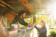 © Martin Barraud/Caia Image - Happy food truck owner serving food to customer in sunny park