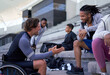 © Trevor Adeline/Caia Image - Wheelchair athlete showing smart phone to friend in stadium bleachers