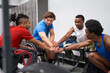 © Trevor Adeline/Caia Image - Amputee and wheelchair athletes joining hands in huddle in locker room