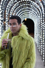 Portrait Fashionable Young Man In Green Fur Coat Under Arch Lights