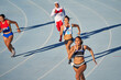 © Trevor Adeline/Caia Image - Female track and field athletes running on sunny blue track